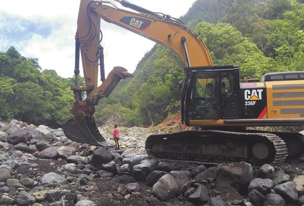 A protester stands in front of an excavator Thursday morning to stop work by Wailuku Water Co. in Wailuku River.